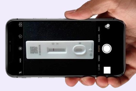A member holding a phone camera over a rapid test